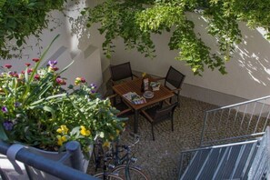 Eine Terrassenfläche mit Tisch und Stühlen, umgeben von Grünpflanzen und einem Fahrrad.