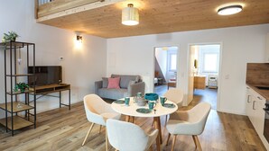 Un espace de vie moderne comprenant un coin repas, un canapé, un téléviseur et une cuisine.
