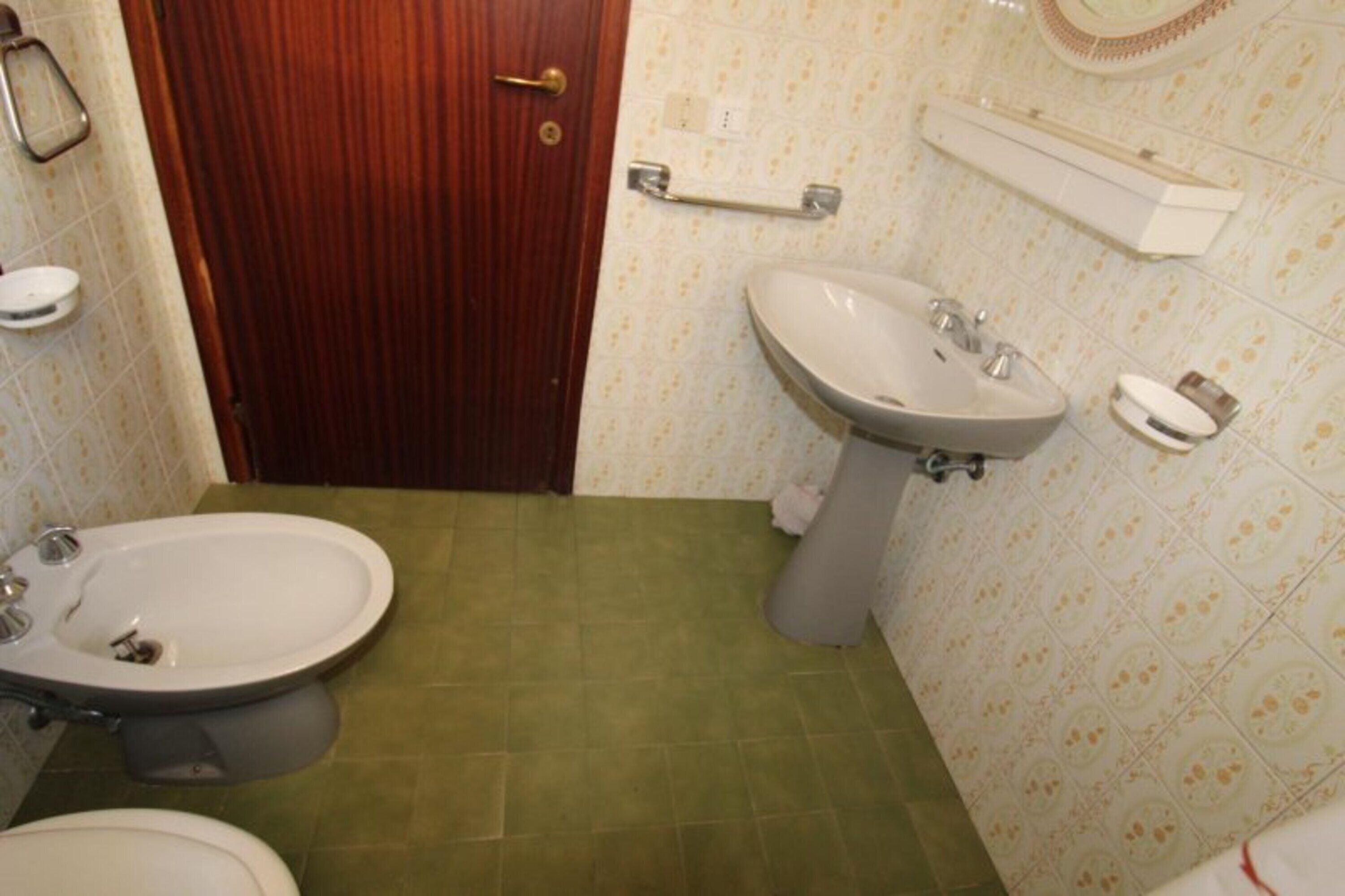 Un baño con puerta de madera, un lavamanos blanco, un bidé y un inodoro.