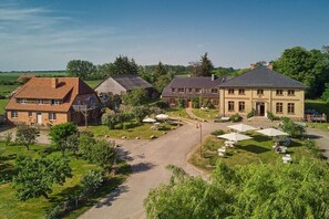 Ein weitläufiges Anwesen mit mehreren Gebäuden, einer gepflasterten Auffahrt und Sitzbereichen im Freien.