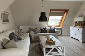 Ein Loft-Wohnzimmer mit weißem Sofa, Couchtisch und Essbereich.