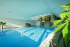 Ein Hallenbad mit Fußball, Treppe und Pflanze.