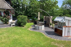 Eine Terrasse mit Feuerstelle, Gartenmöbeln und einem überdachten Sitzbereich.