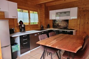 Eine holzgetäfelte Küchenzeile mit Holztisch und -stühlen, einer Kaffeemaschine und einem Spülbecken.