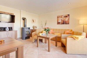 Ein modernes Wohnzimmer mit einer Couch, einem Couchtisch, einem Fernseher und einem Kamin.