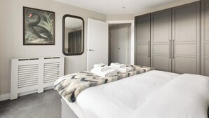 Une chambre à coucher avec un lit, un miroir, un tableau encadré et une armoire.