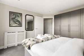 Ein Schlafzimmer mit einem Bett, einem Spiegel, einem gerahmten Bild und einem Kleiderschrank.