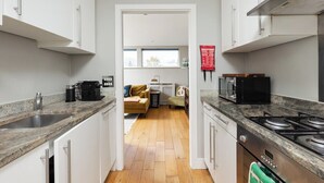 Une cuisine moderne avec des armoires blanches, des comptoirs en granit, une cuisinière à gaz et un four à micro-ondes.
