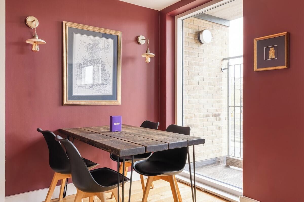 A dining area with a wooden table, black chairs, and a framed map on the wall.