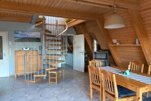 A wooden interior with a spiral staircase, a dining table with chairs, and a kitchen area. - Holiday home in Damp with swimming pool (Damp)