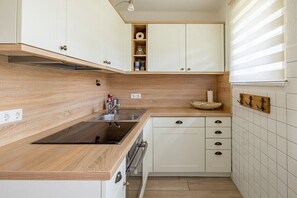 Eine kompakte Küche mit Holzarbeitsplatten, weißen Schränken, einem eingebauten Backofen und einem kleinen Spülbecken.