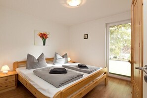 A double bed with grey bedding, a bedside lamp, and a window with a view of trees. - Holiday home with 4 bedrooms (Röbel\/Müritz)