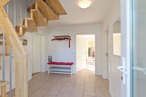 A hallway with a wooden staircase, a bench with red cushions, and a door leading to another room. - Holiday home with 4 bedrooms (Röbel\/Müritz)
