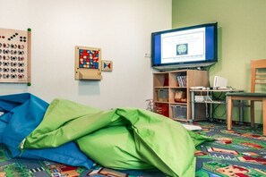 Ein Zimmer mit Bett, Fernseher, Bücherregal und Schreibtisch.