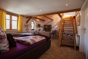 Ein Schlafzimmer mit Bett, Schreibtisch, Stuhl, einer Leiter und einem Fenster.