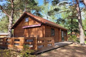 Eine Holzhütte mit rotem Dach, einer Veranda mit Bänken und einer kleinen Haustür.