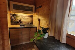 Eine kleine Küche mit Holzwänden, einem Spülbecken, einem Herd und einem Fenster mit Vorhängen.