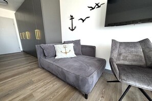A modern living room with a grey sofa, a grey armchair, a flat-screen TV, and decorative wall art.