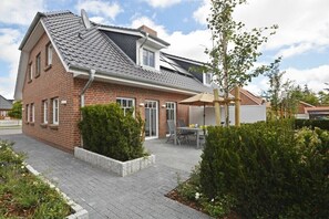 A two-story house with a brick exterior, a sloped roof, and a patio with a table and chairs. - 2 in Veronika's house (Wyk)