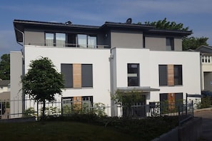 Ein modernes, zweistöckiges Gebäude mit flachem Dach, großen Fenstern und einem Balkon.