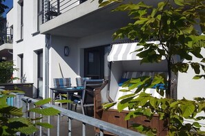 Ein Balkon mit Gartenmöbeln, einem Fenster und einer Tür.