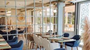 A restaurant with tables set for dining, chairs, and a view through a glass partition. - Status M Apartments 98 (Becici)