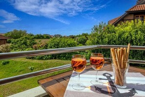 Ein Balkon mit Tisch für zwei Personen, Getränkgläsern und einem Gebäckspiegeleisen.
