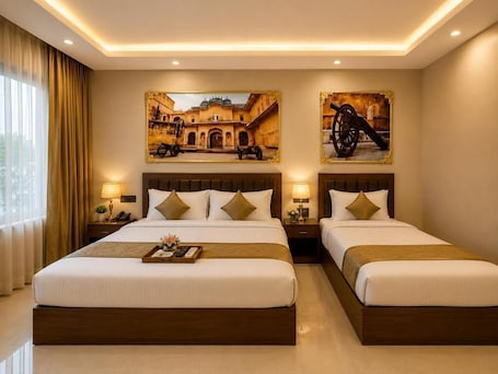 A hotel room with two beds, a large window with curtains, and artwork on the walls.