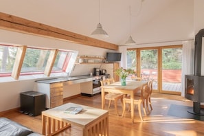 Eine moderne Küche mit Essbereich, Holzbalken, Kamin und Fernseher.