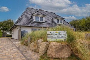 Ein Haus mit Ziegeldach, einem Schild und einem gepflasterten Einfahrt.