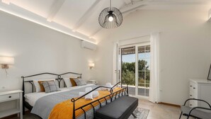 A bedroom with a bed, bedside tables, a bench, a hanging light fixture, and a view through a glass door. - Villa BrickOliva (100551-K1) - Porec (Porec)