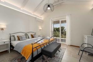 A bedroom with a bed, bedside tables, a bench, a hanging light fixture, and a view through a glass door. - Villa BrickOliva (100551-K1) - Porec (Porec)