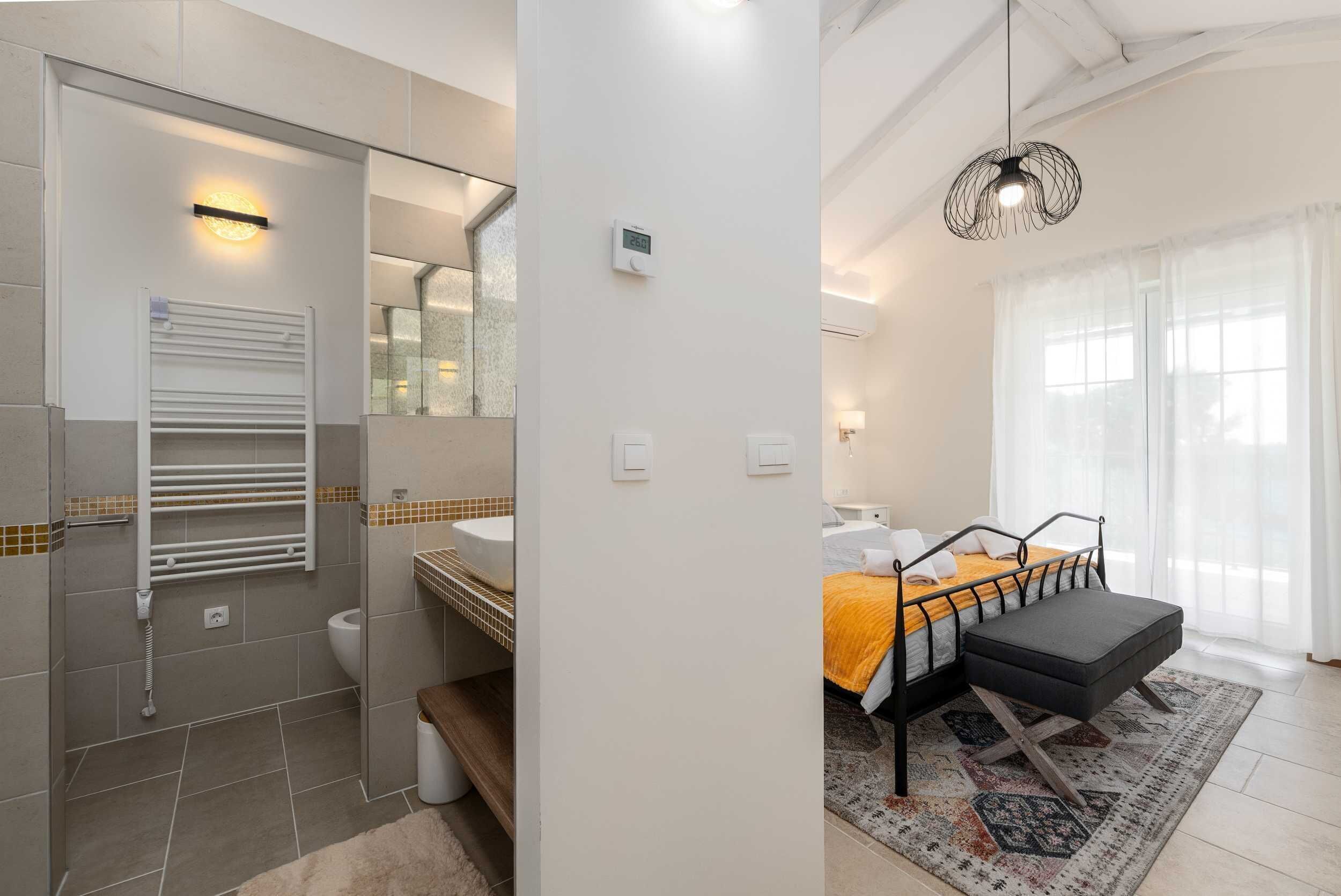 A modern bathroom with a glass shower enclosure, a white sink, and a towel rack.