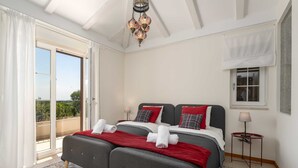 A double bed with red and white bedding, a small bedside table with a lamp, and a balcony with a view. - Villa BrickOliva (100551-K1) - Porec (Porec)
