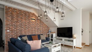 A living room with a brick wall, a sofa, a coffee table, a TV, and hanging lights. - Villa BrickOliva (100551-K1) - Porec (Porec)