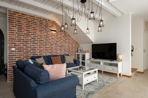 A living room with a brick wall, a sofa, a coffee table, a TV, and hanging lights. - Villa BrickOliva (100551-K1) - Porec (Porec)