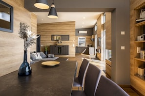 Ein modernes Wohnzimmer mit einem dunklen Holzesstisch, grauen Sofas und einer schwarzen Vase.