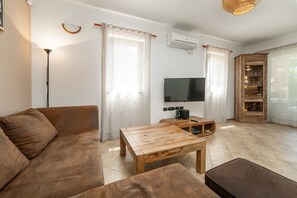 Ein Wohnzimmer mit einer Couch, einem Couchtisch, einem Fernseher und einem Holzkasten.
