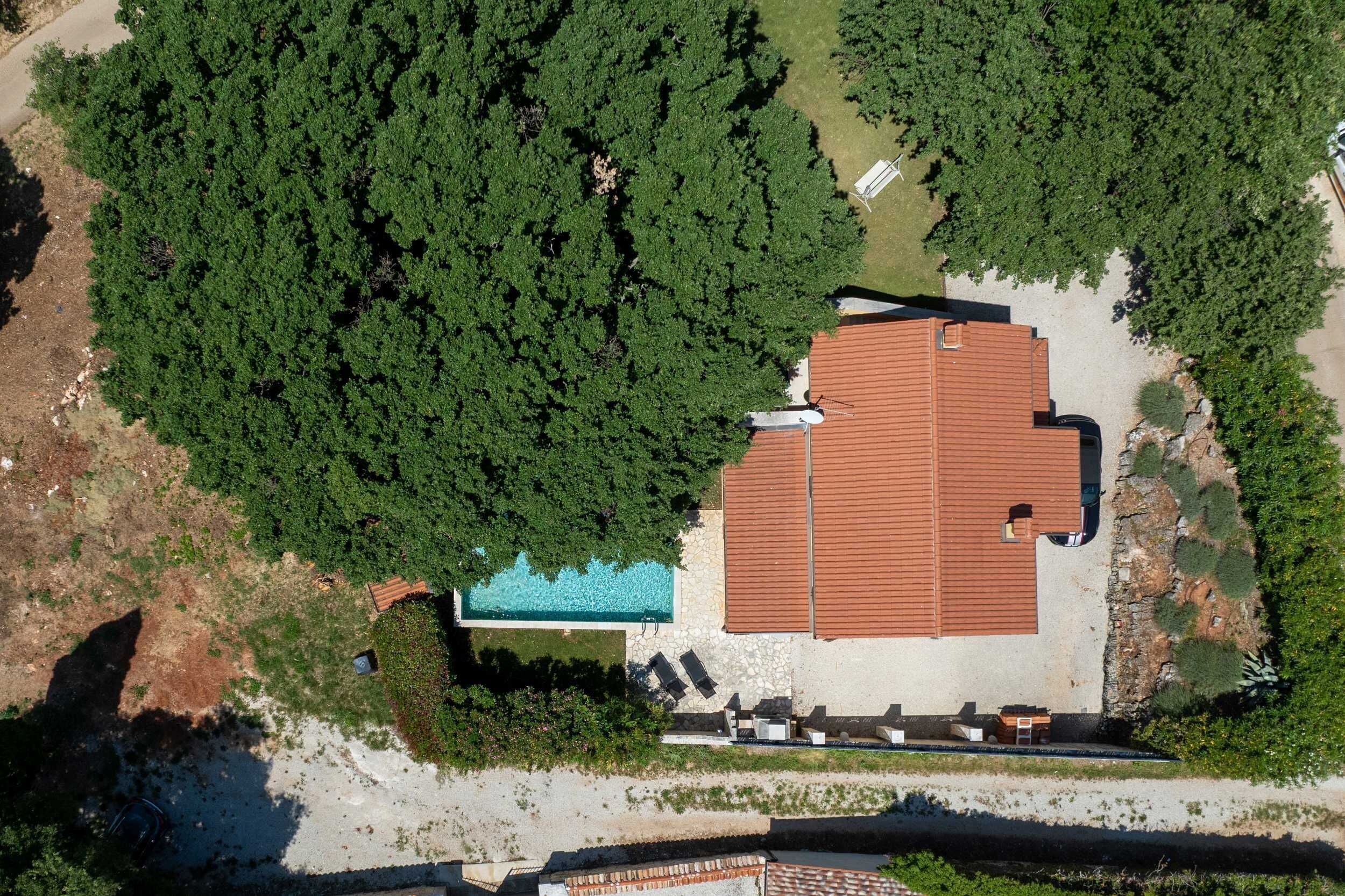 Vista aérea de una propiedad con piscina, terraza cubierta y amplia zona descubierta.