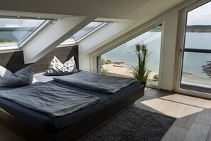 Ein Schlafzimmer mit Oberlicht, einem Bett und Seeblick.