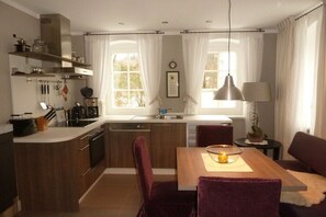 A modern kitchen with a central island, wooden cabinets, and a dining area with a table and chairs. - Holiday apartment in Neuhausen with sauna (Neuhausen)