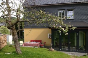 A house with a dining area, a tree with blossoms, and a garage door. - Holiday apartment in Neuhausen with sauna (Neuhausen)