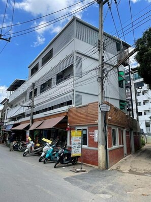 A multi-story building with a ground-level commercial space, a visible signboard, and parked motorcycles. - Banhor Residence (AMPHOE MUEANG CHIANG MAI)