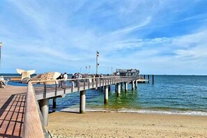 A pier extending into the water with a wooden walkway, benches, and a flagpole. - Holiday apartment with 1 bedroom (Oldsum)