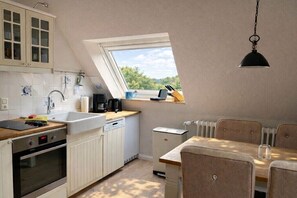 Eine kleine Küche mit Fenster, ein Essbereich mit Tisch und Stühlen sowie eine Heizung.