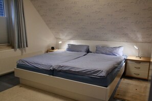 Une chambre à coucher avec un lit, des tables de chevet et une fenêtre avec des rideaux.