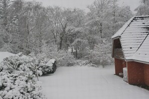 Schneebedeckte Landschaft mit einem Holzhaus und Bäumen.