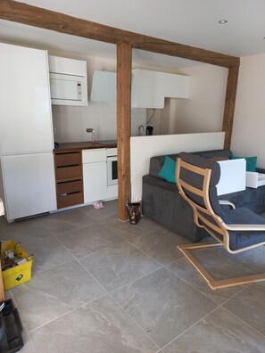 A modern kitchen with white cabinets, a wooden beam ceiling, and a grey sofa with teal cushions. - Charming, in a typical chalet and hamlet (Les Contamines-Montjoie)