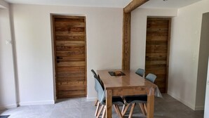 A dining area with a wooden table and chairs, a wooden accent wall, and a tiled floor. - Charming, in a typical chalet and hamlet (Les Contamines-Montjoie)