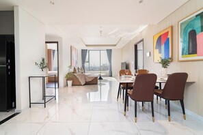Een moderne woonkamer met een eethoek, een bank, een televisie en uitzicht op de stad.